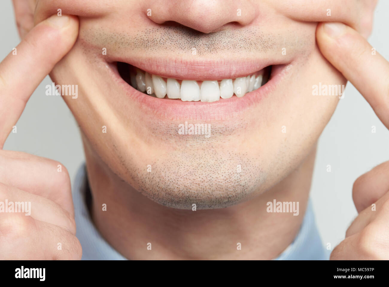 Making fake smile with teeth and fingers close up Stock Photo