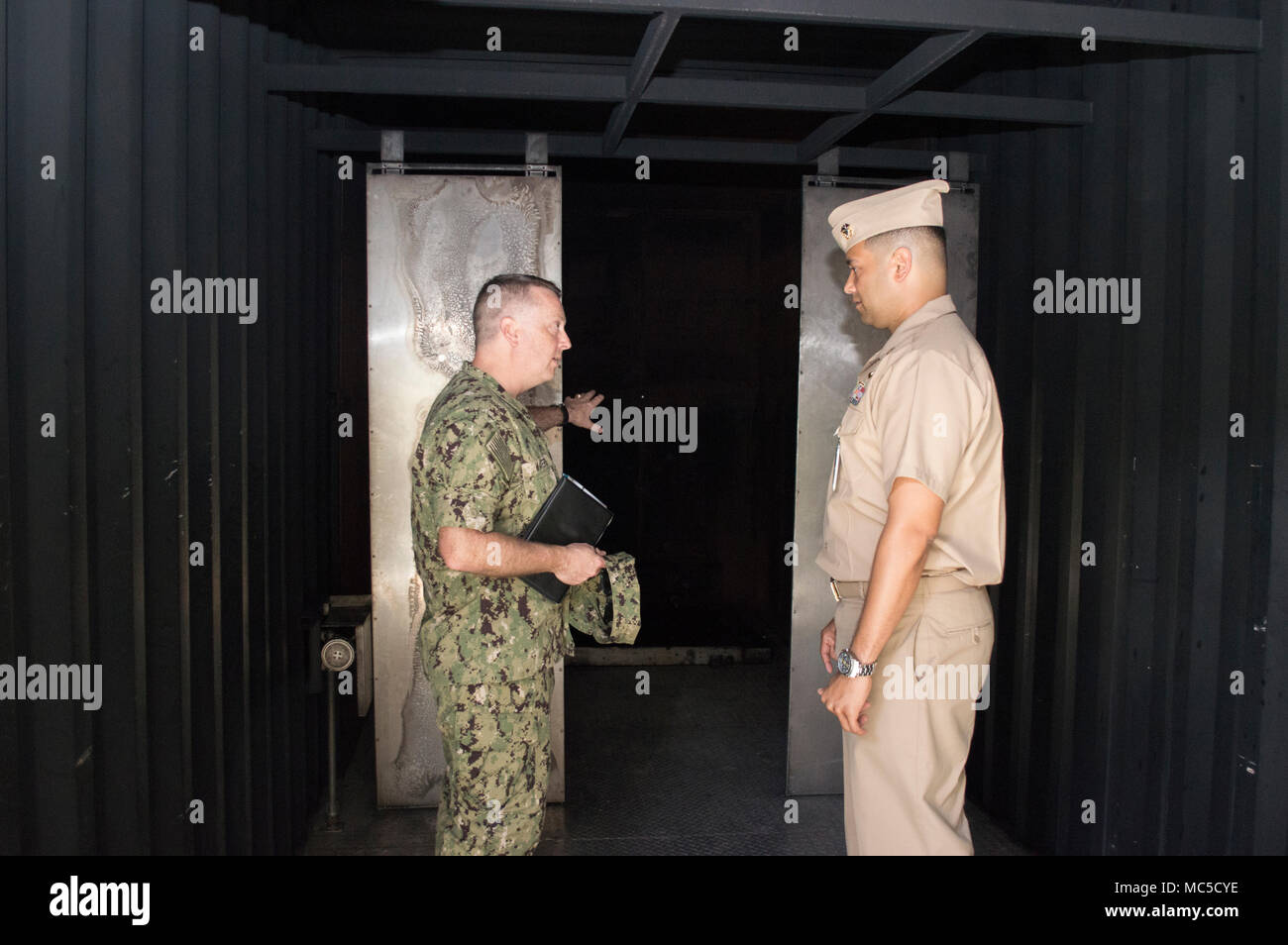 180402-N-WI626-039 SANTA RITA, Guam (April 2, 2018) Rear Adm. James Waters III, director, Maritime Headquarters, U.S. Pacific Fleet, left, discusses the capabilities of Naval Submarine Training Center Pacific detachment (NSTCP det) Guam's mobile firefighting trainer, MT-1000, with Lt. Jeffrey Cornielle, NSTCP det Guam Officer in Charge, during a tour of the training facility, April 2. Waters met with Navy commands across Guam to discuss ship maintenance and logistical capabilities and concerns. (U.S. Navy photo by Lieutenant Lauren Spaziano/RELEASED) Stock Photo