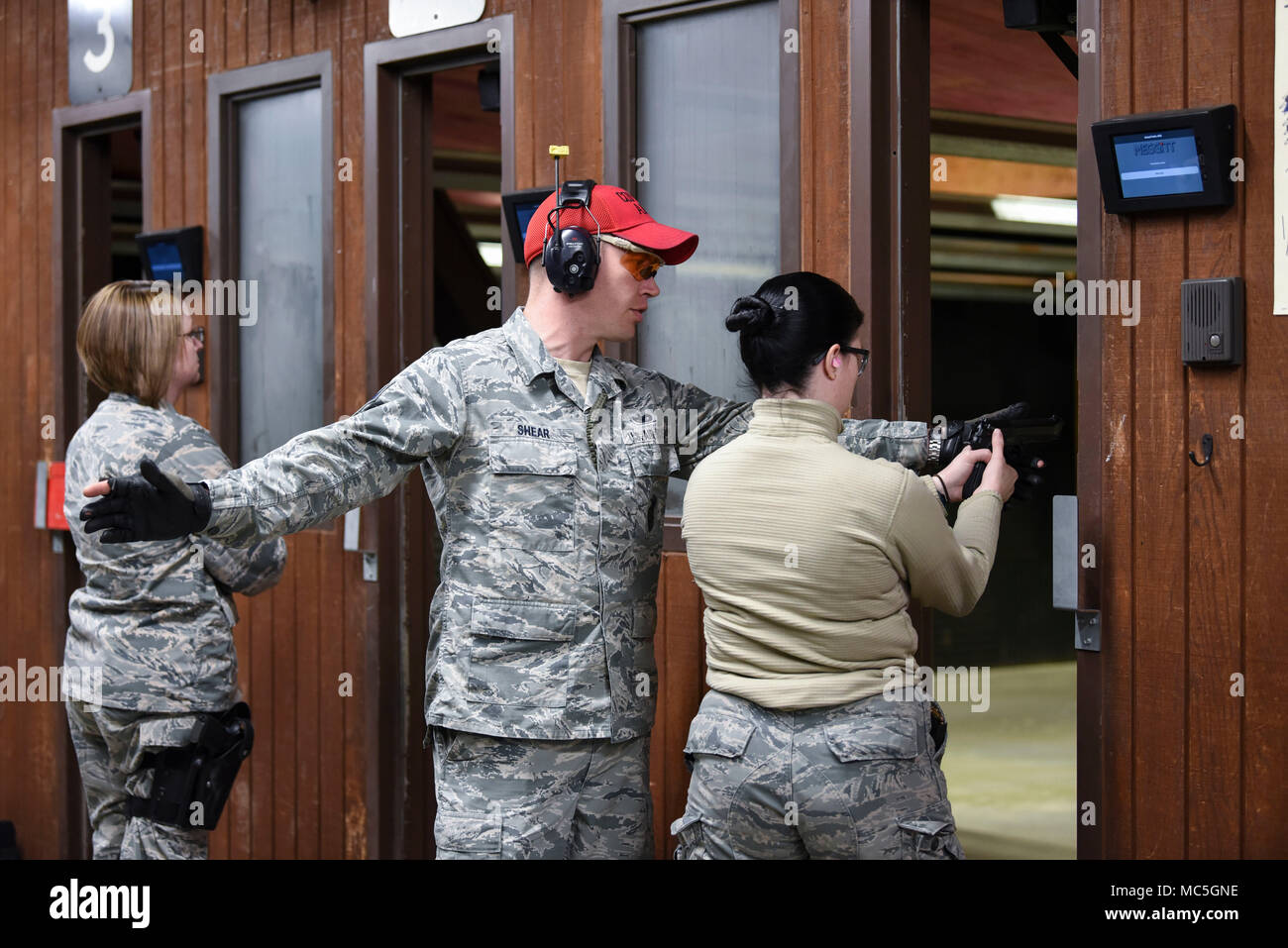 Air Force Staff Sgt. Randy Shear, a 319th Security Forces Squadron firearms instructor, assists