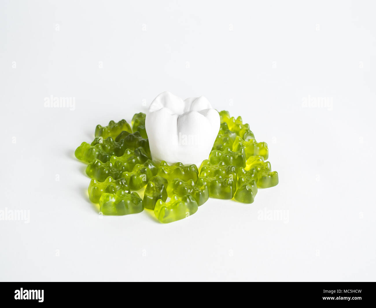The tooth is surrounded by sweets on the white background Stock Photo