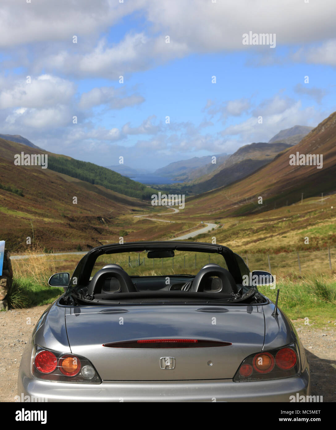 A silver sports car parked at the Glen Docherty viewpoint, part of the North coast 500 scenic drive, Scotland,uk. Stock Photo