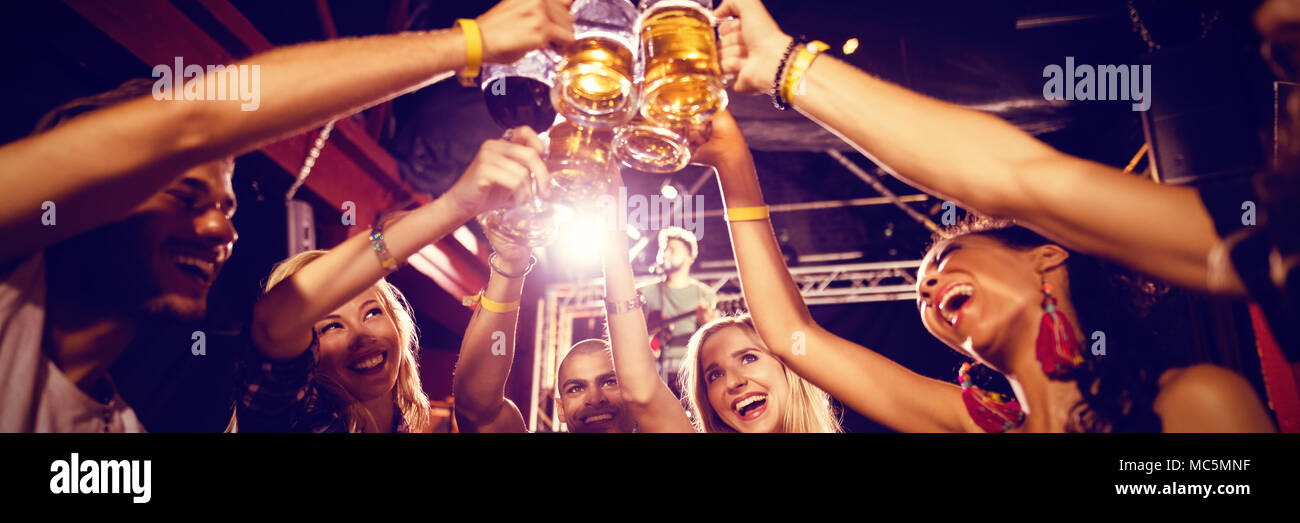Friends toasting beer glasses at table in club Stock Photo