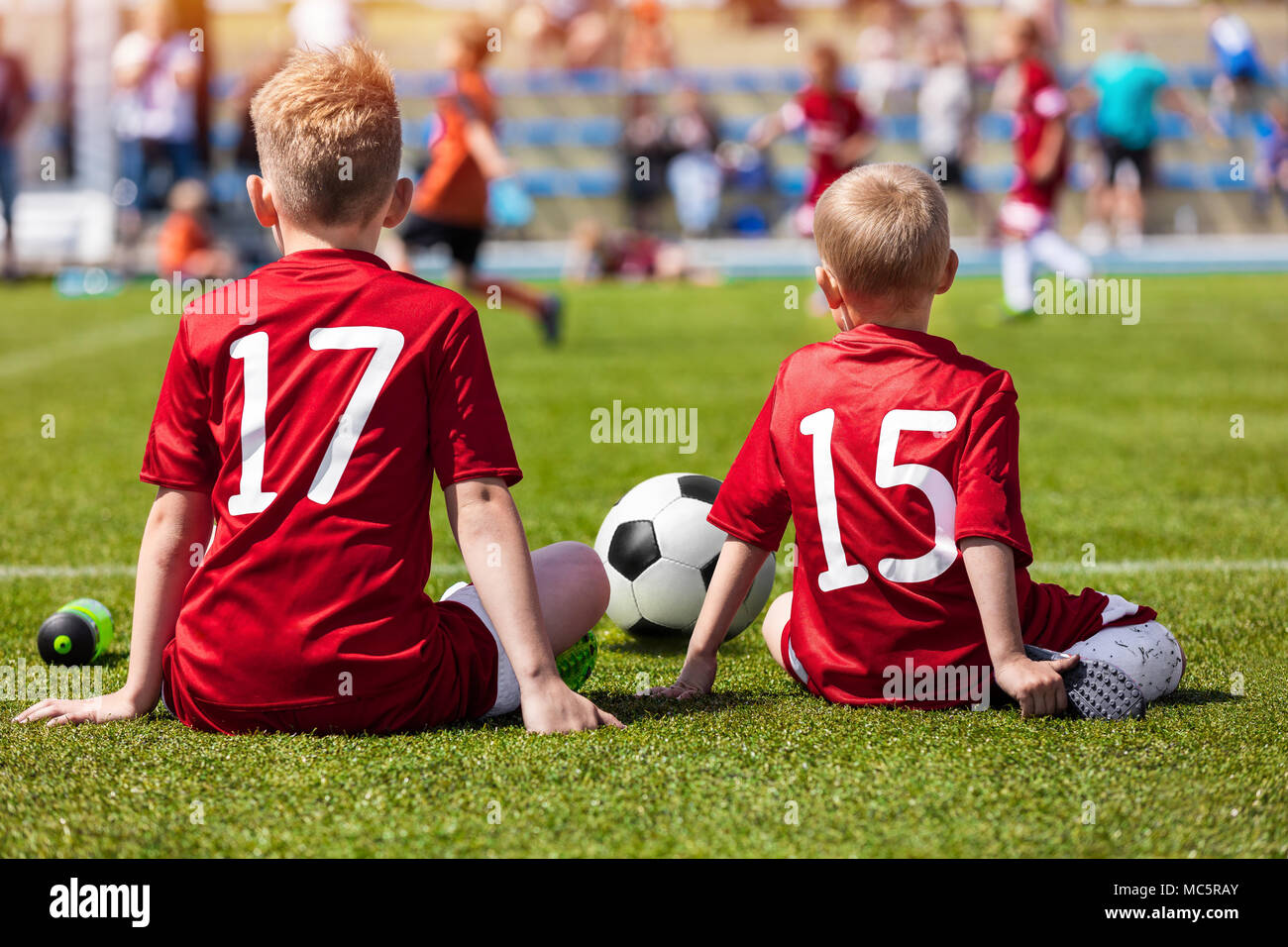Coaching Kids Soccer. Young Boys Sitting on Football Field and Watching Tournament Game. Football Match for Children Stock Photo