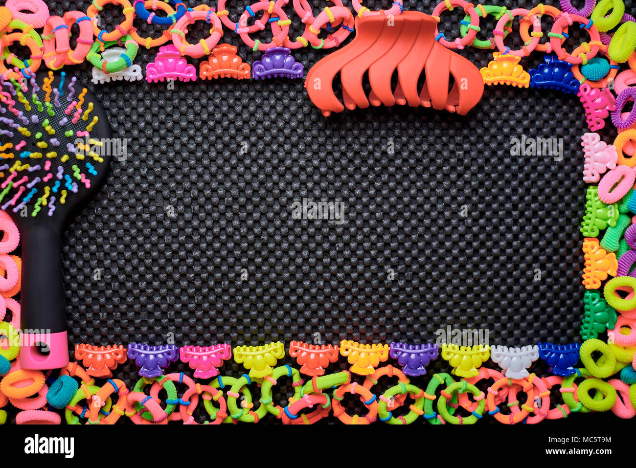 A frame of multi-colored colorful rubber bands for hair, combs and hair clips on a black background.Copy space. Stock Photo