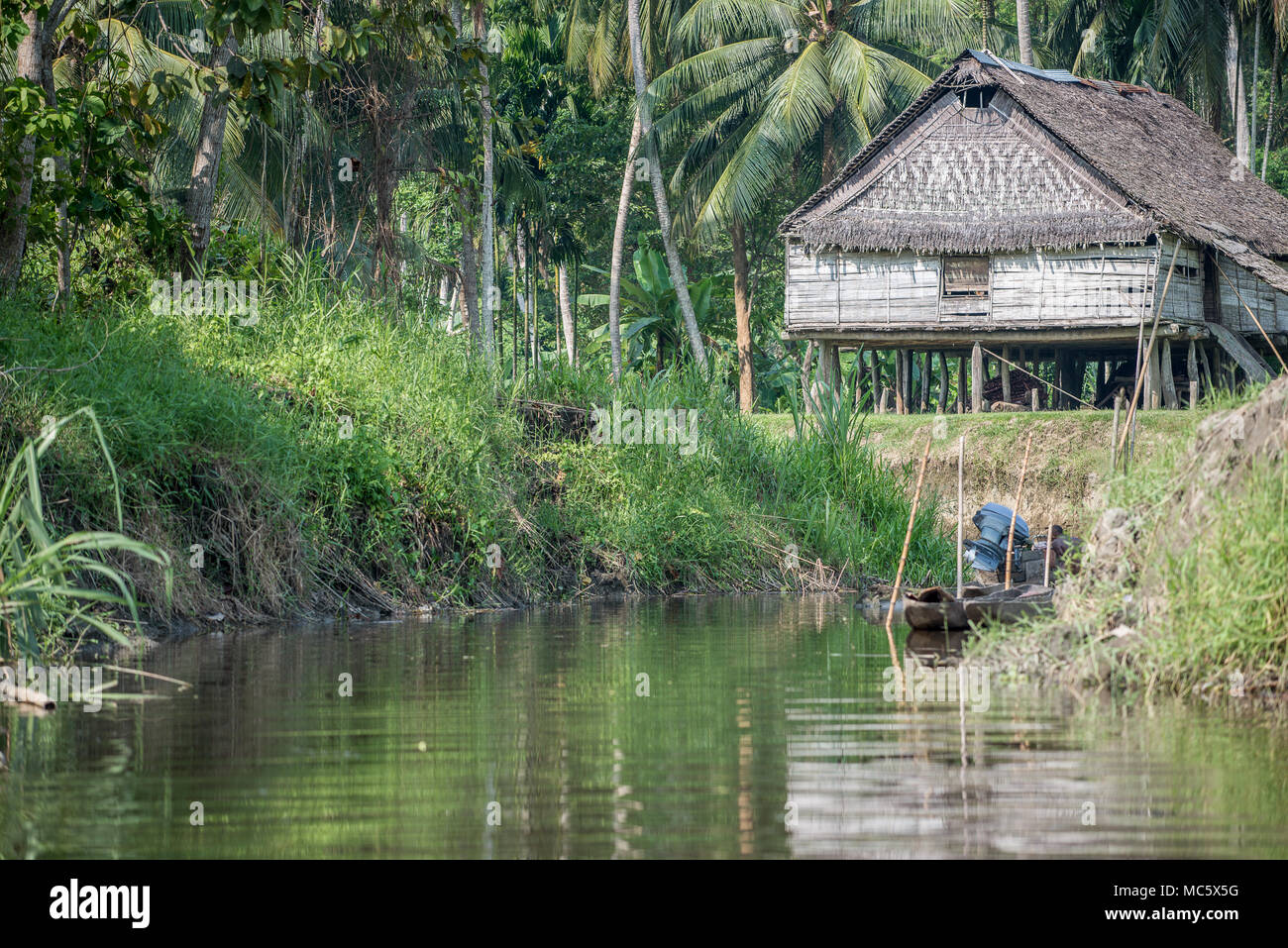 An outboard motor dugout canoe moored close to a stilt house, Kanganaman Village, East Sepik Province, Papua New Guinea Stock Photo