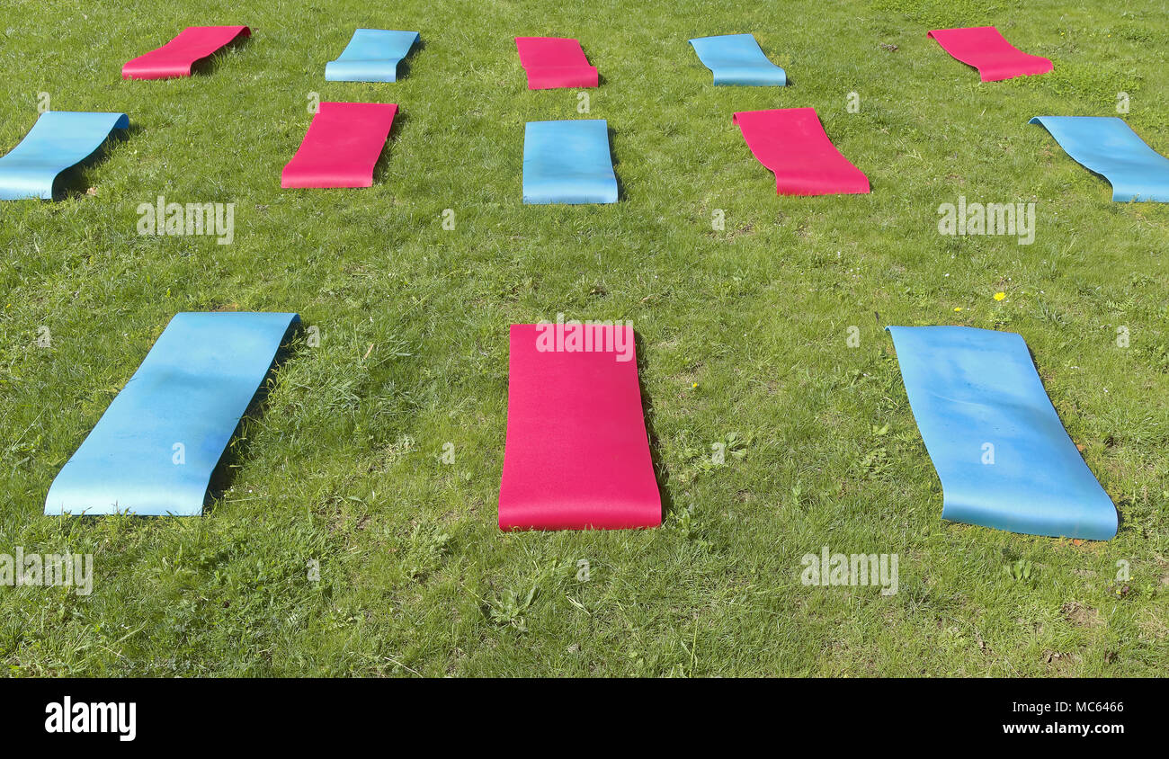 fitness mats prepared on green lawn waiting to be used for outdoor physical activity Stock Photo