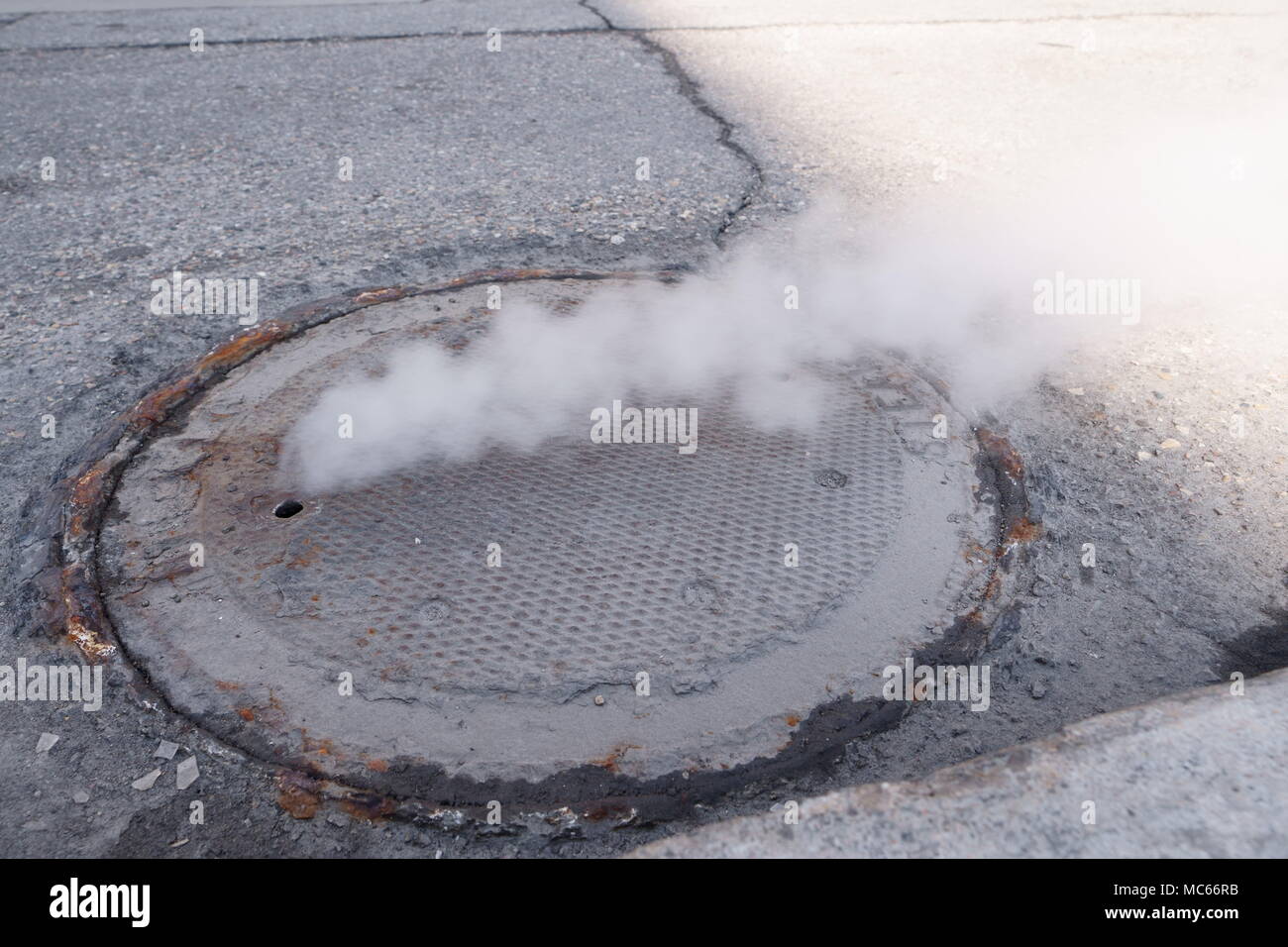 Heavy steam coming out of a city center sewer. Stock Photo