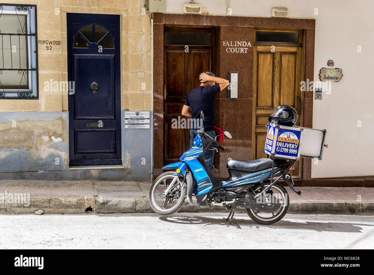 Puzzled pizza delivery man on moped, Triq santa marija, Pauls Bay, Malta, Europe, Stock Photo