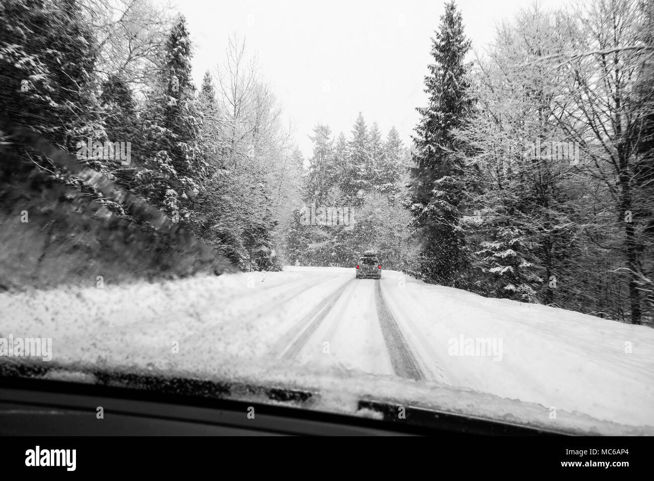 Car driving during winter snow taken through a windshield covered with blured snowflakes. Stock Photo