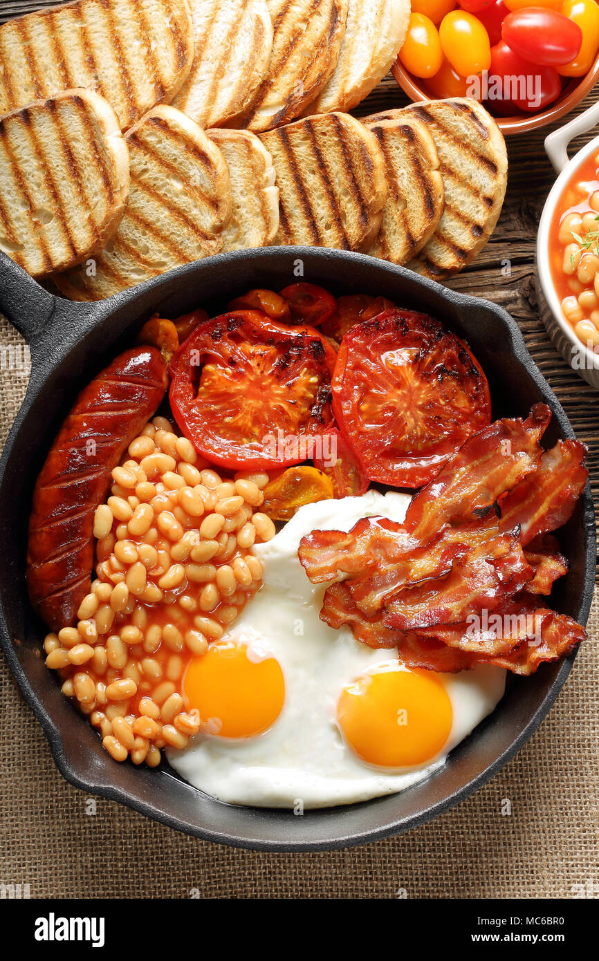 English Breakfast with sausages, grilled tomatoes, egg, bacon and beans ...