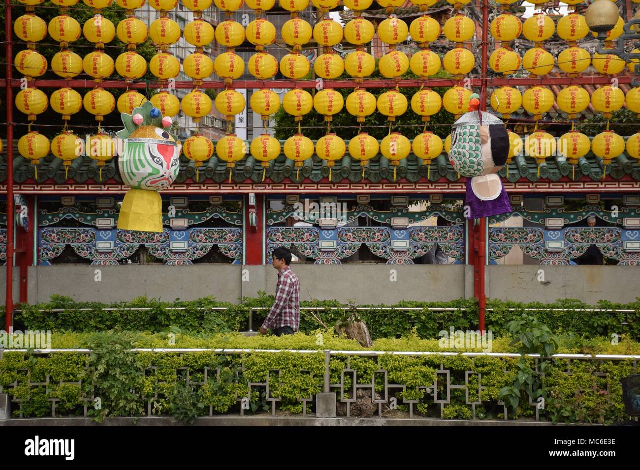 Asian man walking beside yellow lanterns outside Longshan buddhist temple, Taipei - Taiwan Stock Photo
