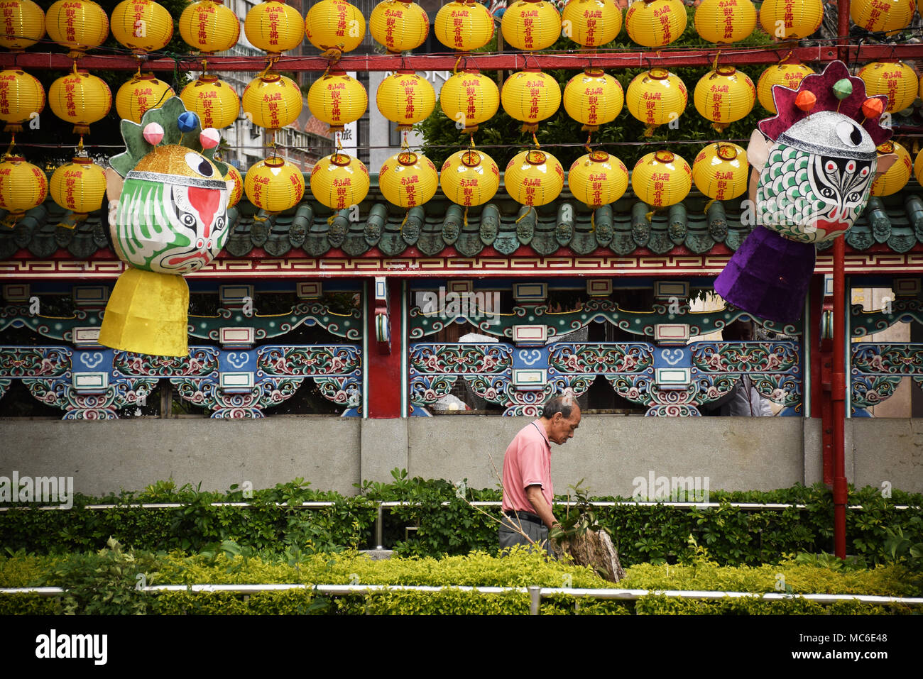 Old asian man walking beside yellow lanterns outside Longshan buddhist temple, Taipei - Taiwan Stock Photo
