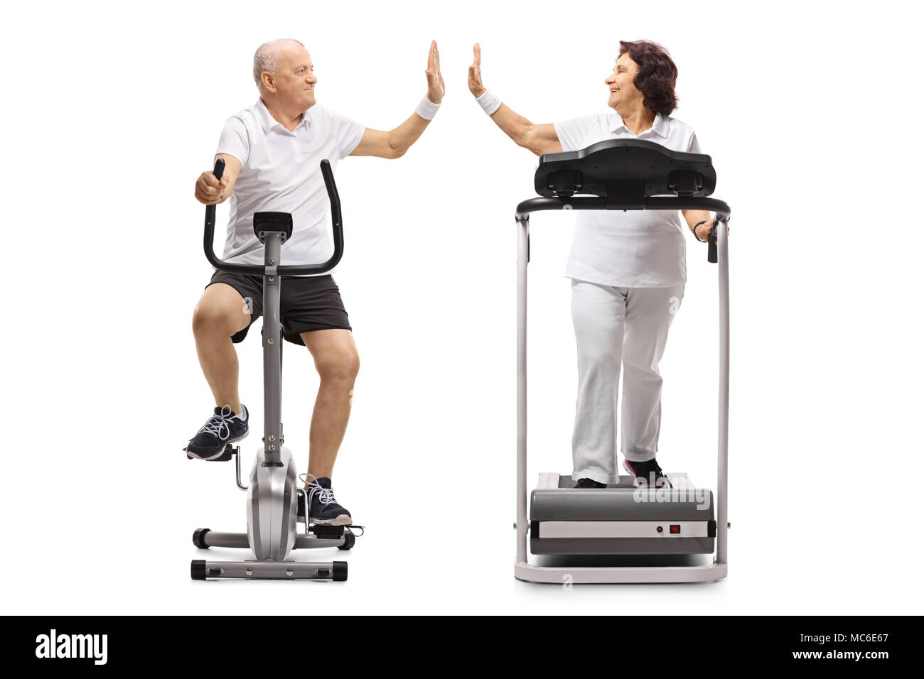 Elderly man exercising on a stationary bike and an elderly woman on a  treadmill high-fiving each other isolated on white background Stock Photo -  Alamy