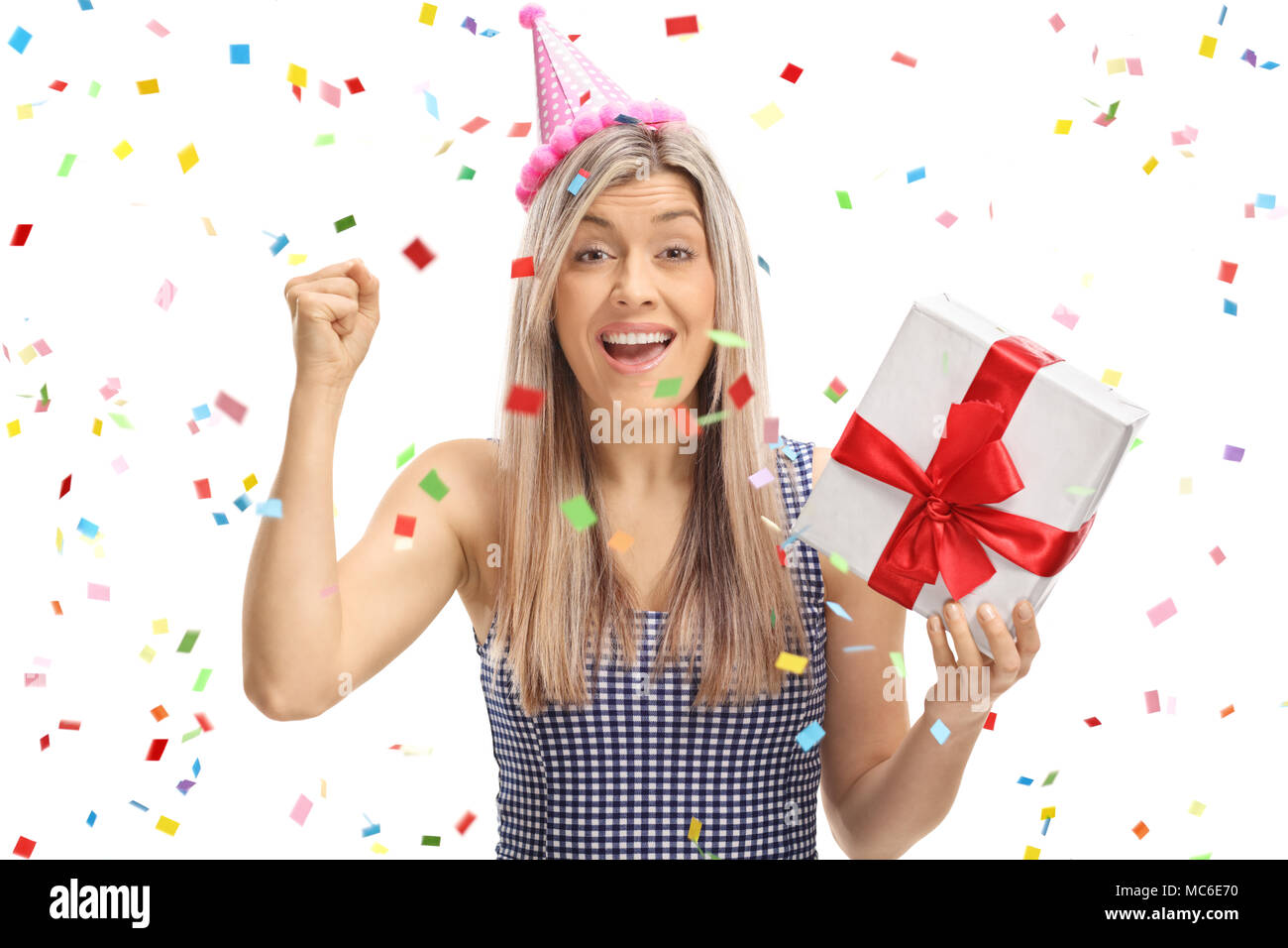 Joyful young woman holding a present with confetti streamers flying around her isolated on white background Stock Photo