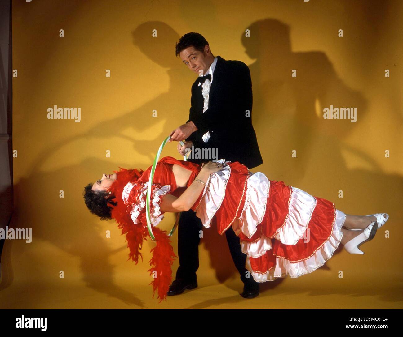 STAGE MAGIC - The magician who has caused the woman to float in the air (levitate) passes a hoop along her body to show that she is not being supported, and that there is no trickery Stock Photo