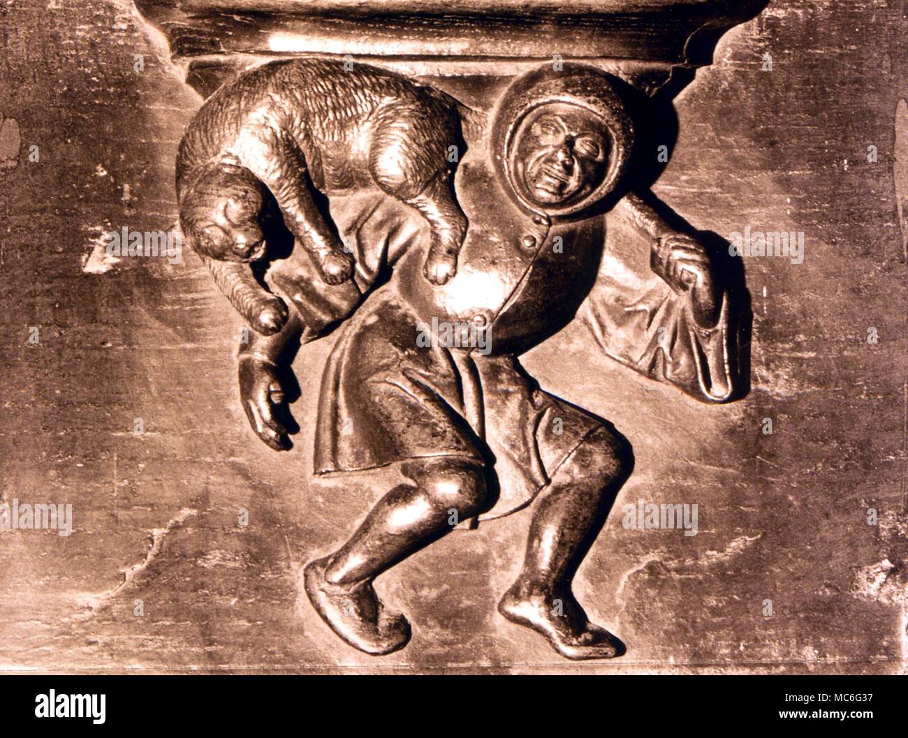 ANIMALS Image of a man throwing a cat - from a 15th century misericord in the stalls of St Sulpice church, Diest, Belgium Stock Photo