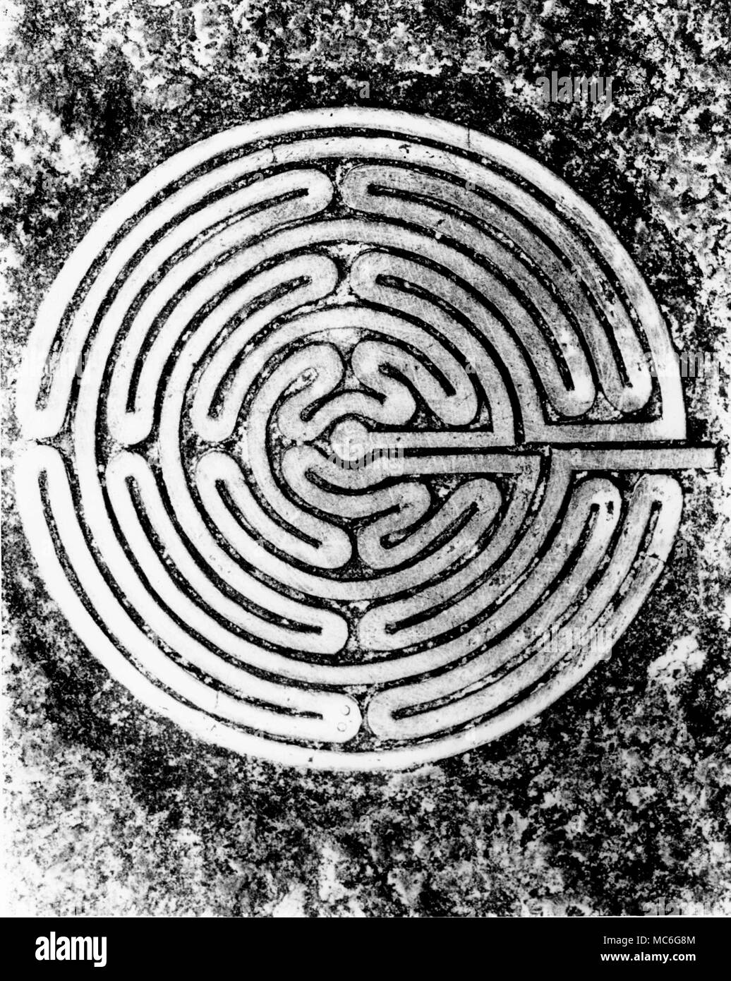 MAZES - THE ALKBOROUGH MAZE - JULIAN'S BOWER Photograph of a bronze copy of the mediaeval maze known as Julian's Bower, at Alkborough, on a gravestone in the local cemetery. The original turf maze is 12 metres in diameter [colour pictures of this maze are available in the Charles Walker archives). In addition to being used for this grave-stone, the ground plan has been adopted for details in the masonry and stained glass of the local parish church (colour images of all these are in the Charles Walker archives). The Alkborough maze is not a pure maze, or labyrinth, for once having embarked u Stock Photo