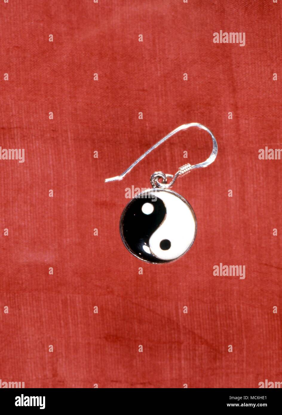 AMULETS - Amuelt earring in the form of the Chinese Tai Chi with the alternating yin and yang forces (darkness and light) each with a speck of its opposite contained withing the centre of its bowl Stock Photo