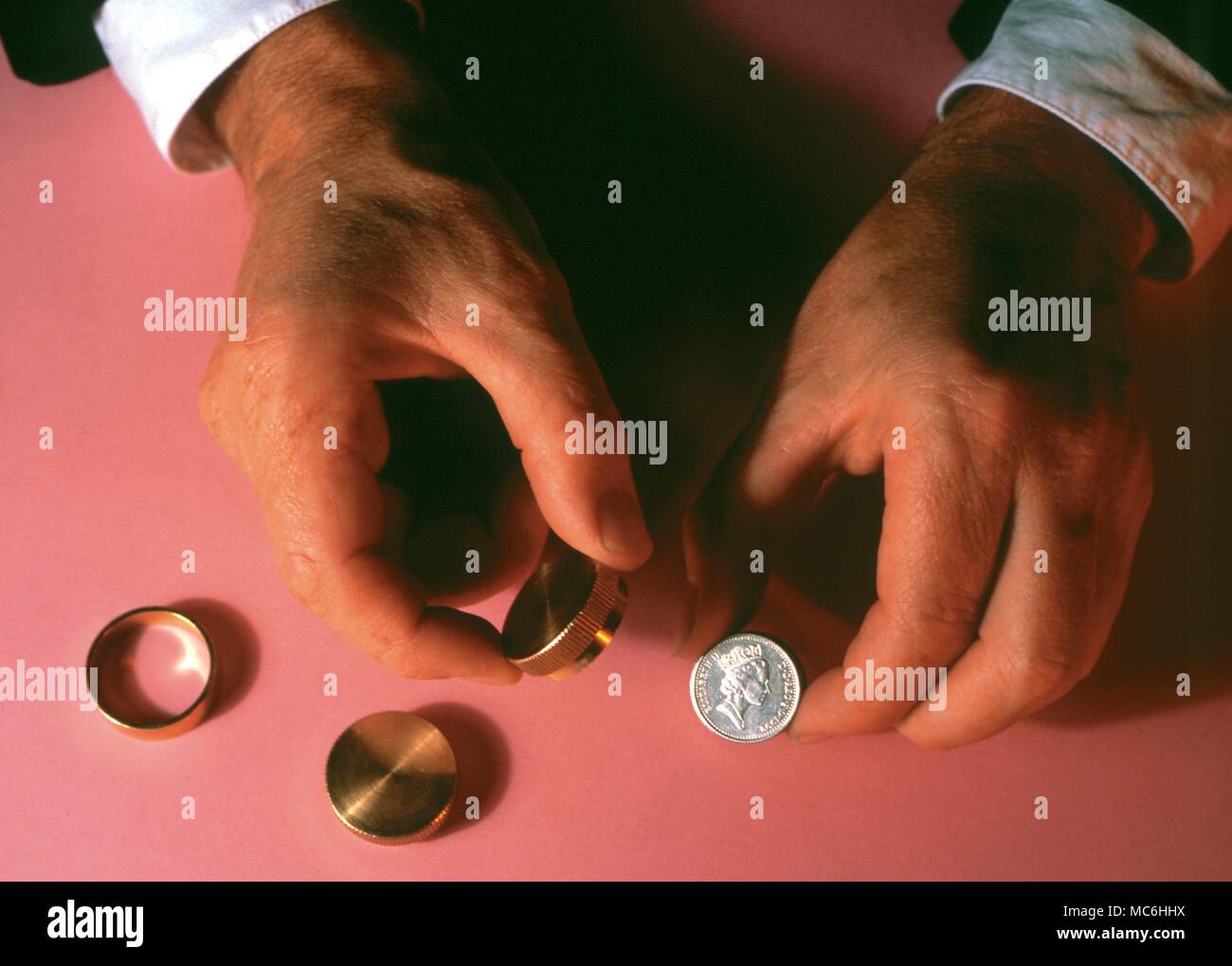 Magicians Hands performing coin tricks. Sleight of hand. Stock Photo