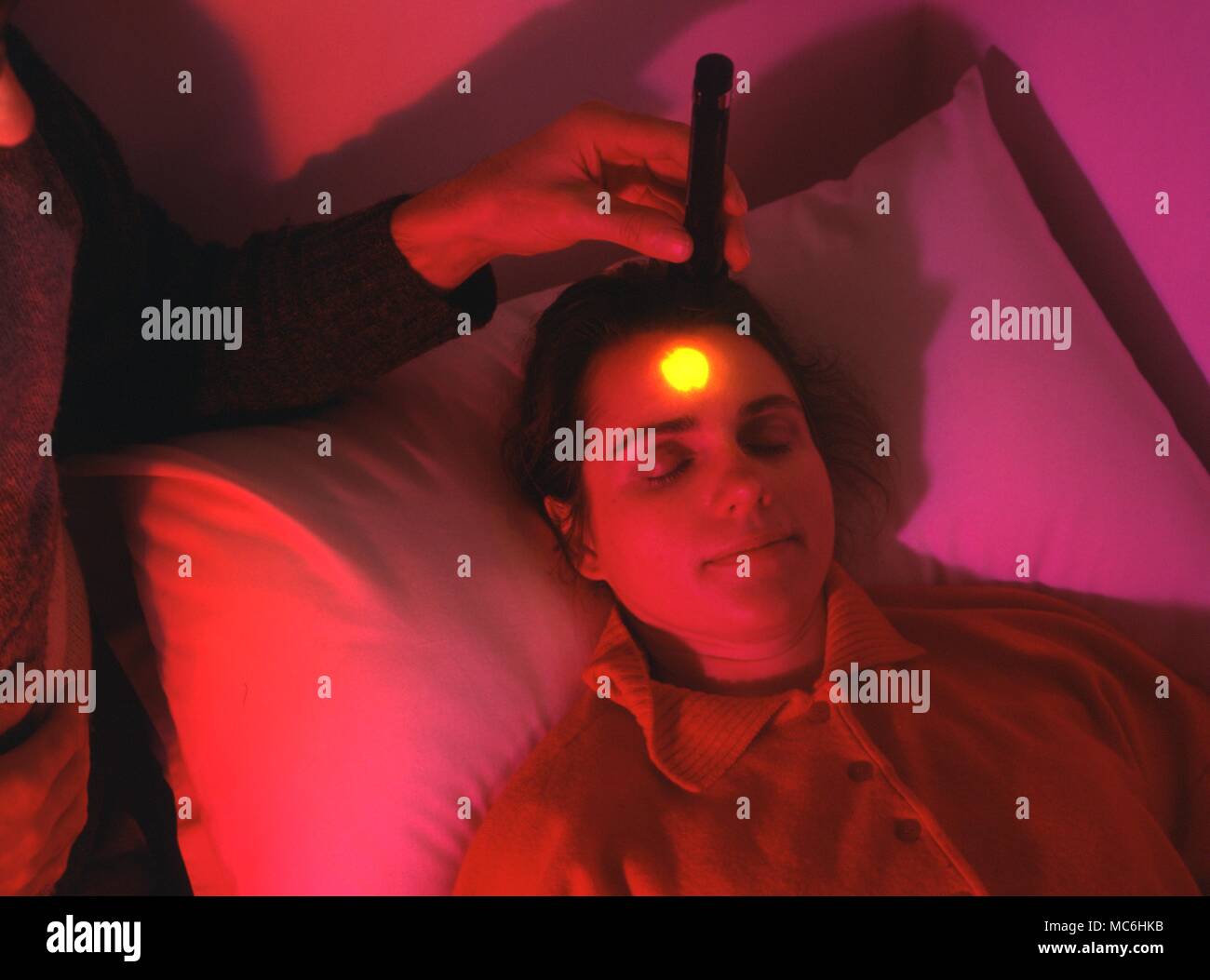 Colour Therapy. Projecting a light on the frontal chakra, in a room lighted with complimentary colour. Stock Photo