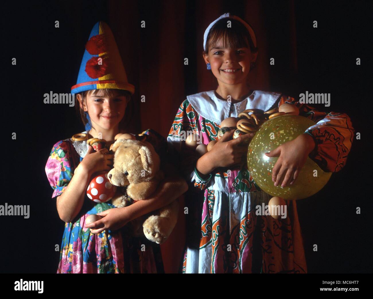 Stage Magic. The magician takes object after object from his hat, and hands them to two children. Soon, they cannot carry everything and begin to drop objects on the stage. Stock Photo