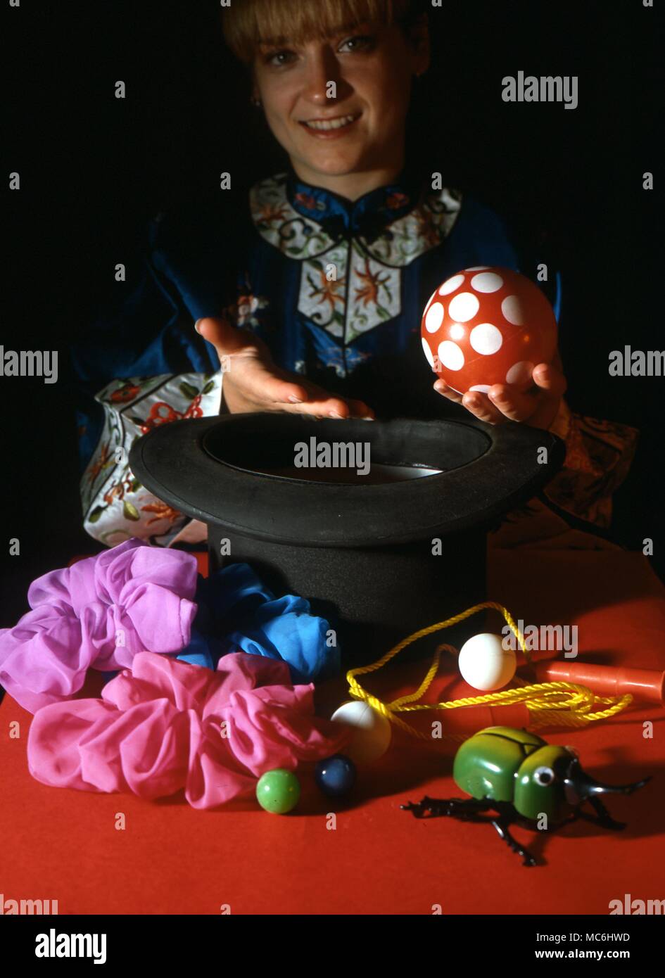 Stage Magic. The girl magician shows that the top hat is empty and then proceeds to take an enormous number of objects from it. Stock Photo