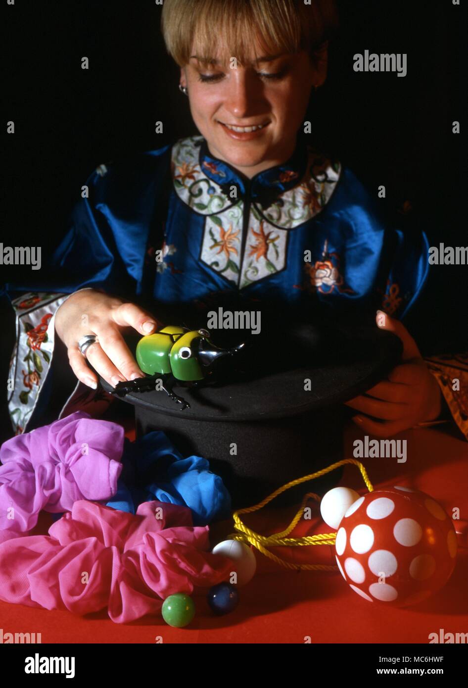 Stage Magic. The girl magician shows that the top hat is empty and then proceeds to take an enormous number of objects from it. Stock Photo