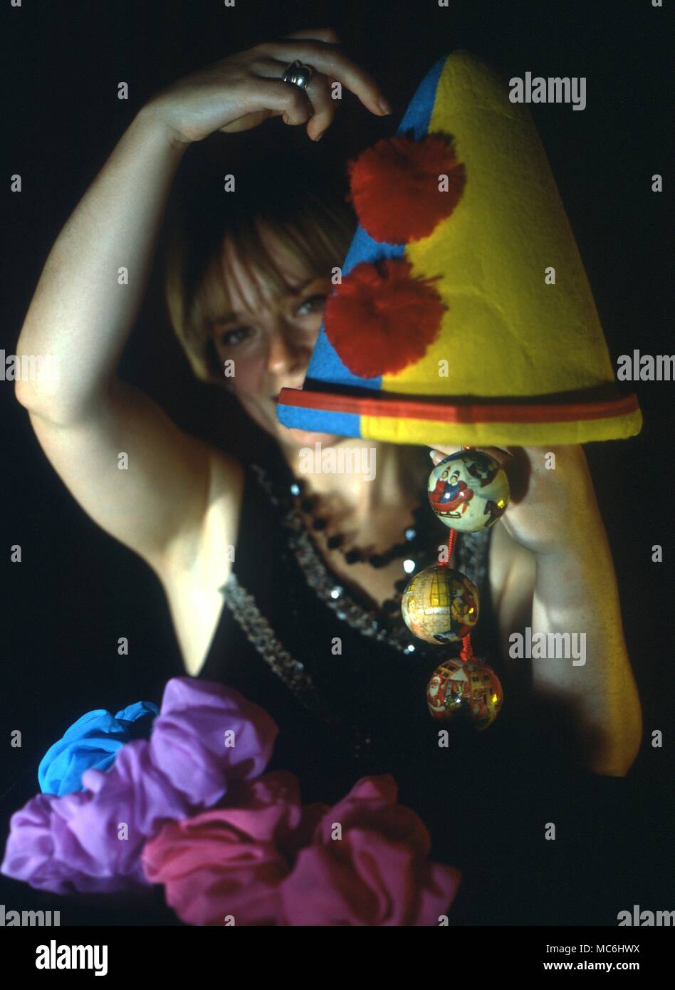 Stage Magic. The girl magician shows that the clown's hat is empty and then proceeds to take an enormous number of objects from it. Stock Photo