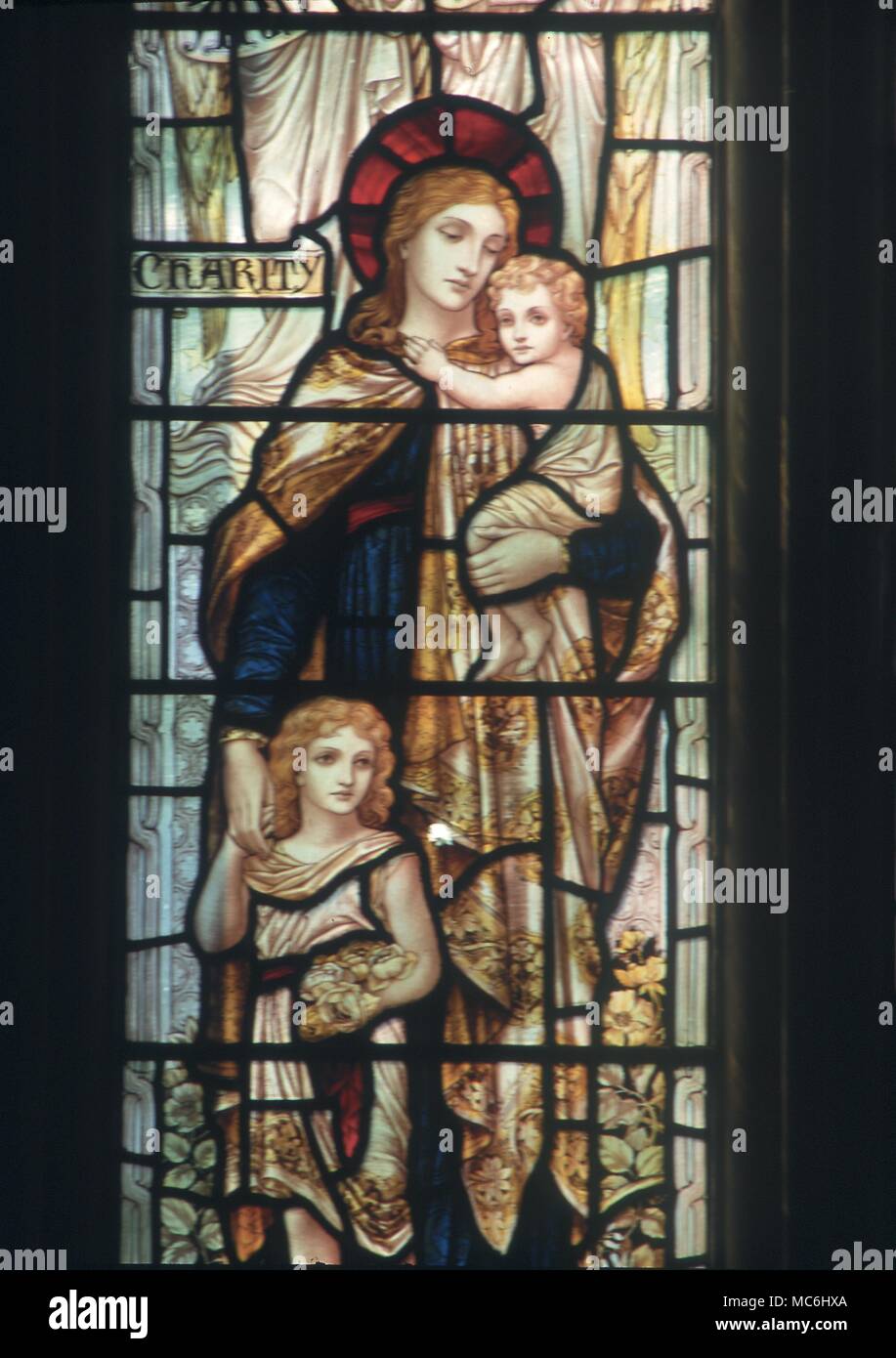 Symbol of Charity. Woman with two children depicted in a stained glass window in the church of St Mary, Godstone.Surrey Stock Photo