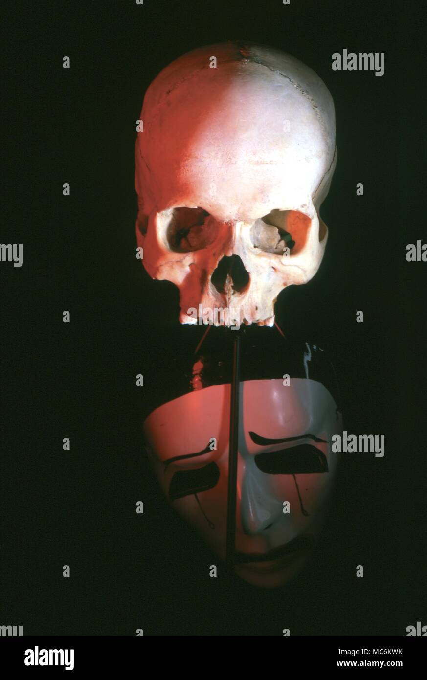 Mask. Weeping carnival mask below a human skull - an allegory of Death Stock Photo