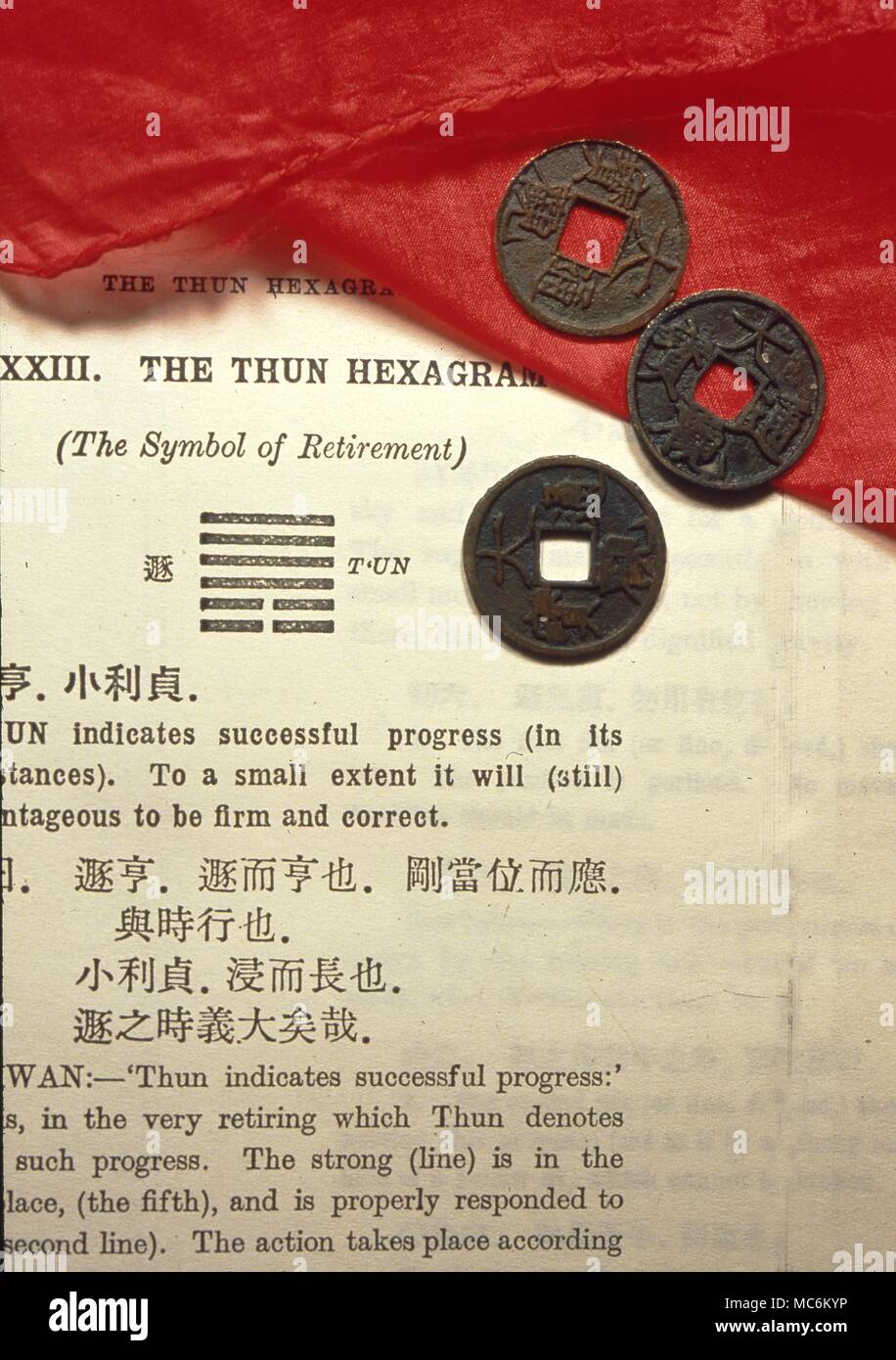 I Ching Three Chinese coins used for divination in the I Ching system, laid on a page from the I Ching. Stock Photo