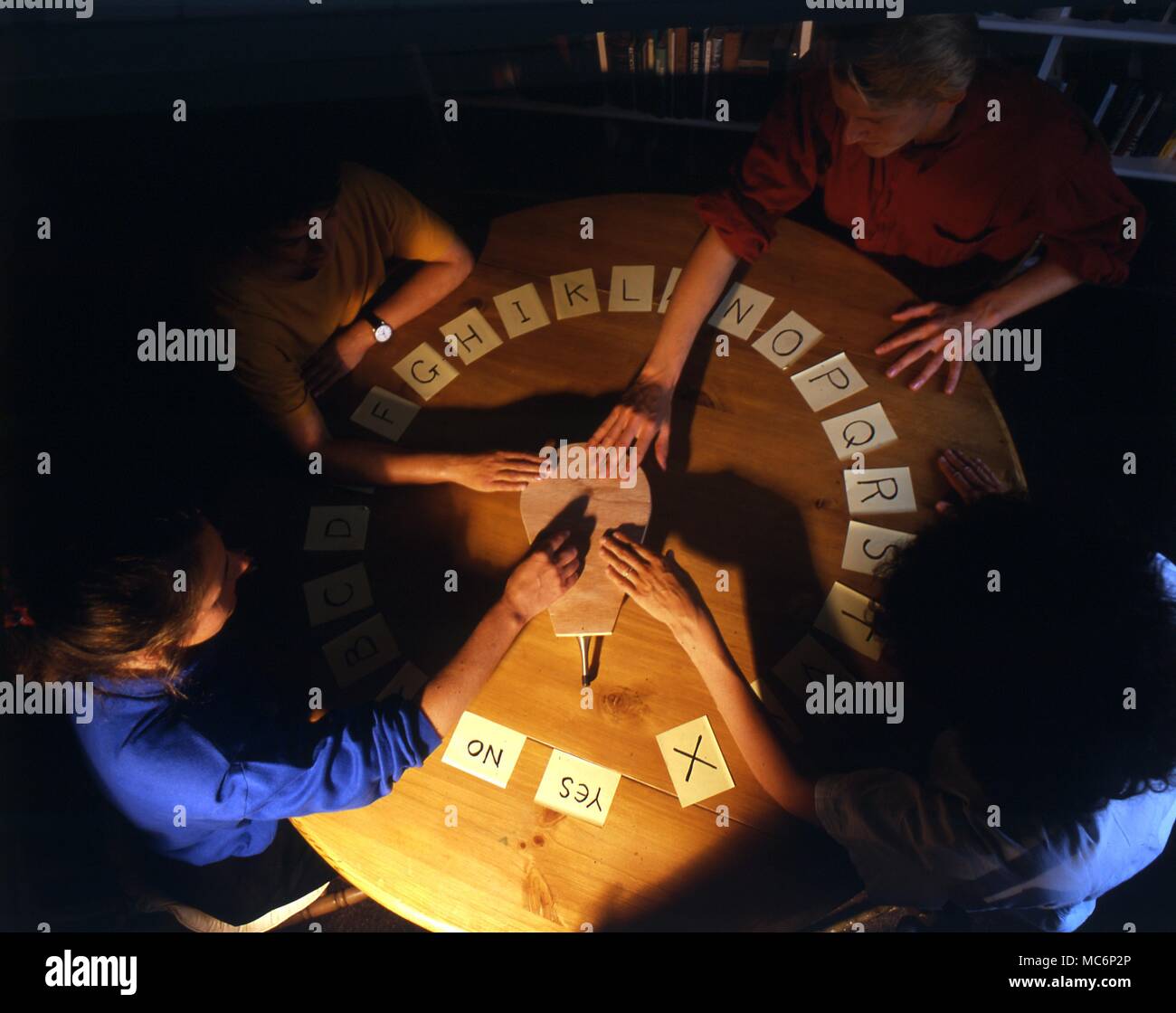 Ouija- Four people practising the Ouija table, with the aid of a simple planchette, or device designed to move easily in any direction. 2004 Charles Walker / Stock Photo