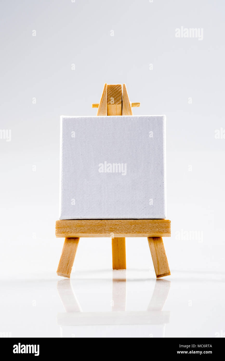 Little tripod wood easel with square white canvas. Stock Photo