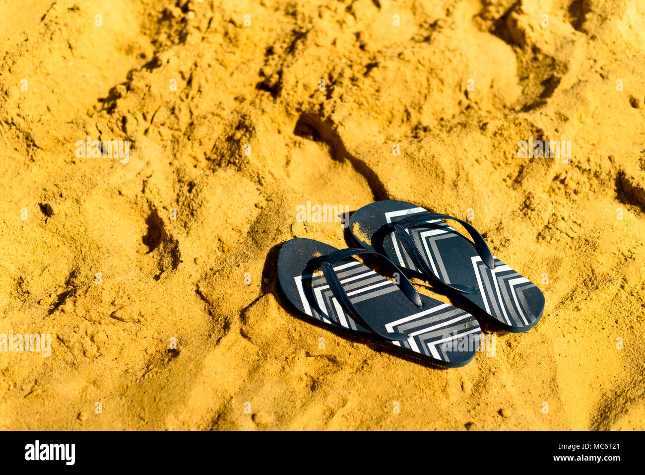 Summer slippers. Navy blue flip flop on yellow sand beach background ...