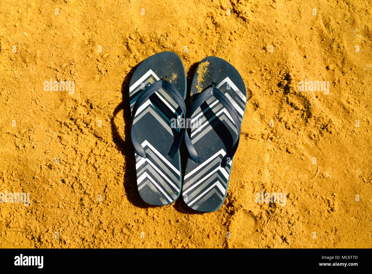 Summer slippers. Navy blue flip flop on yellow sand beach background ...