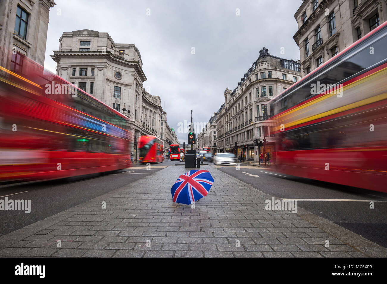London, England - British umbrella at busy Regent Street with iconic red double-decker buses on the move Stock Photo