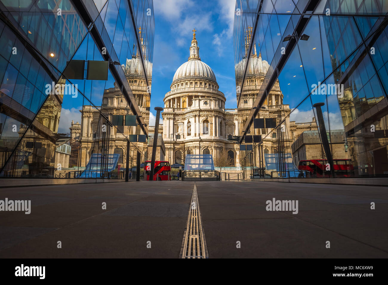 London, England - Beautiful St.Paul's Cathedral reflected in glass windows in the morning sunlight with iconic red double-decker bus and blue sky Stock Photo