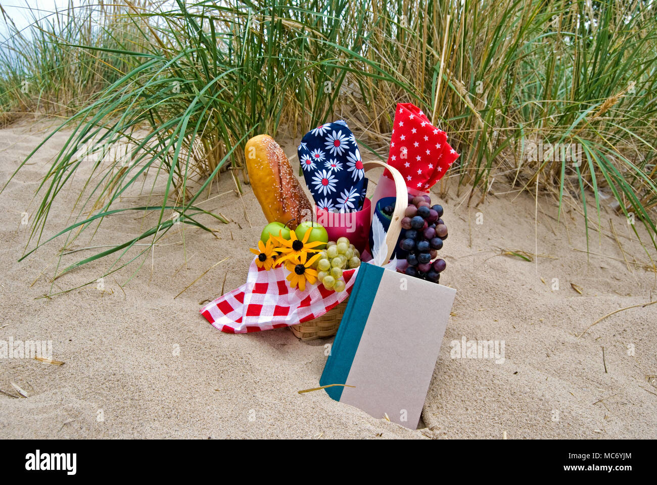 Picnic basket with food and book on beach sand Stock Photo - Alamy