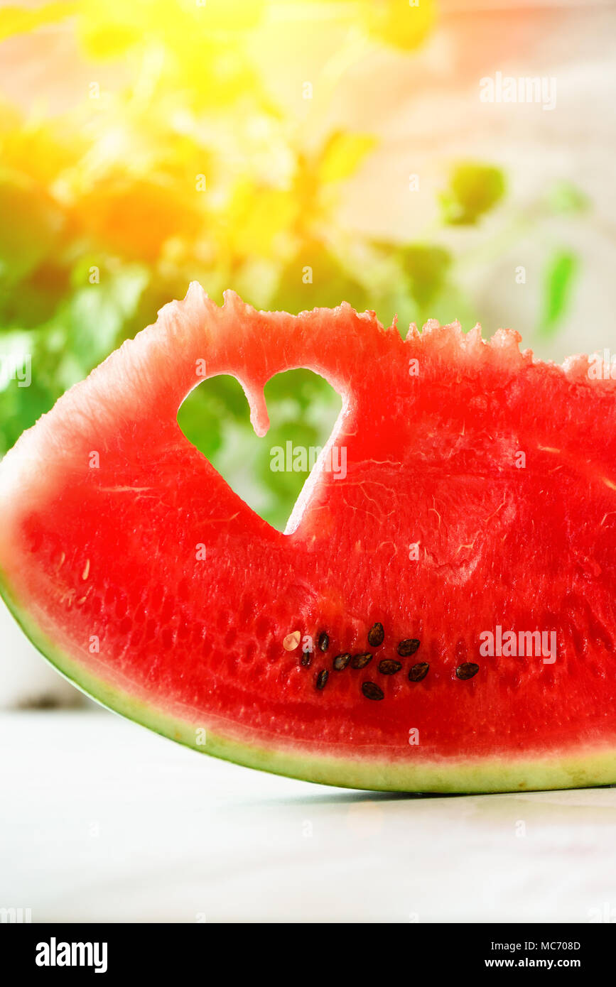 Piece of watermelon with heart shape on grey concrete background. Copy space. Flat lay. Greeting card, love concept. Valentine's Day. Stock Photo