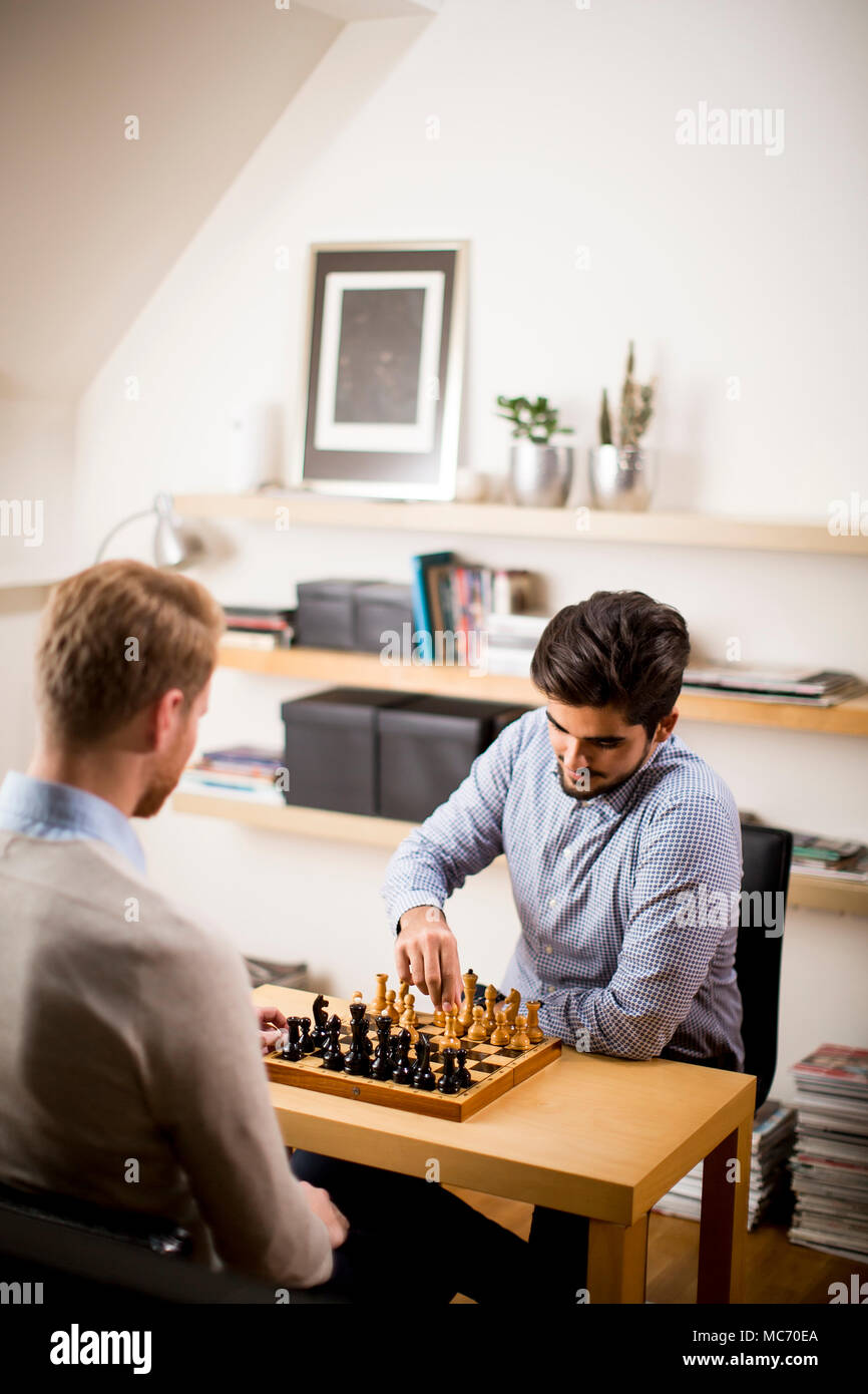 Two young men playing chess in room Stock Photo