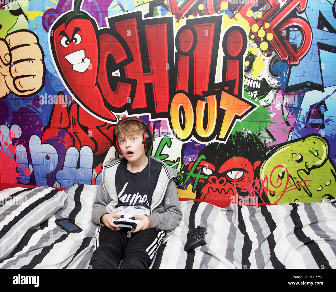 Boy playing on Xbox one in his bedroom Stock Photo