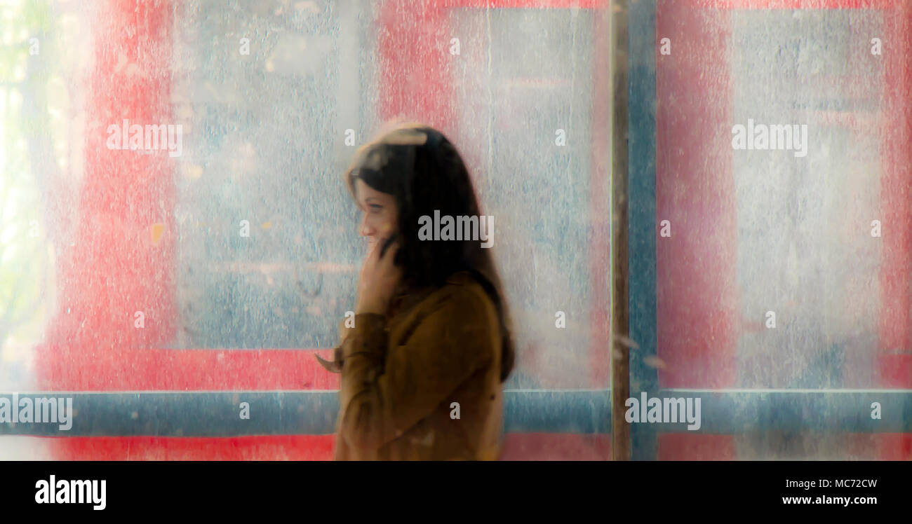 Belgrade, Serbia - April 11, 2018: Blurry young woman walking out of the subway passage and a moving traffic  behind her, with glass reflections and b Stock Photo