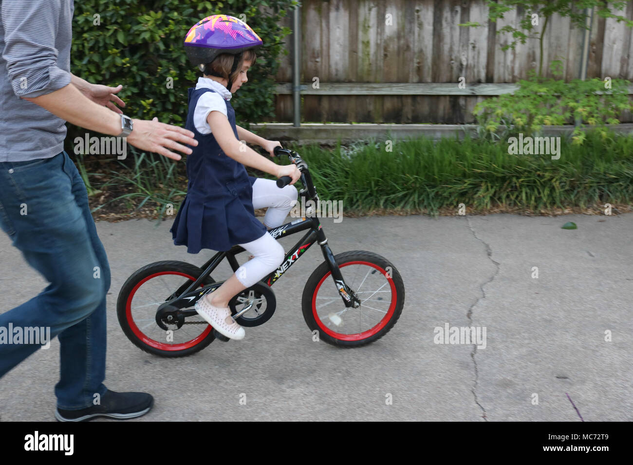 Father helping little girl to ride a bike Stock Photo