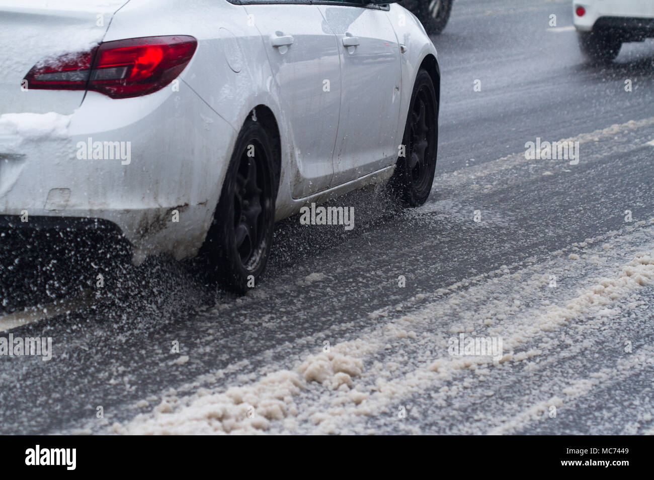 closeup rear view of a car white color wheel tire going through snow on