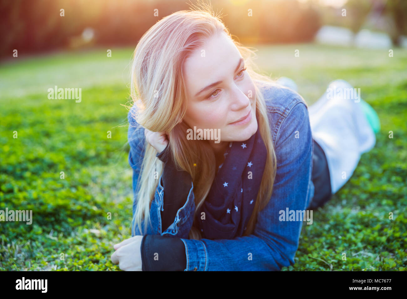 Portrait of a beautiful woman relaxing outdoors, lying down on the ...