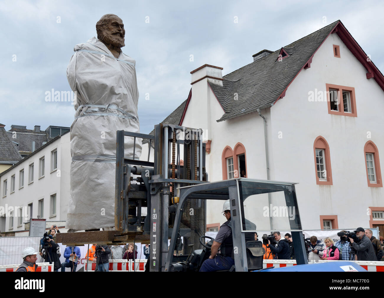 13 April 2018, Germany, Trier: Workers from a building company mounting the 2.3 ton, 4.4 metre high, canvas covered Karl Marx statue from the Chinese artist Wu Weishan in Trier. The official unveling will take place on 05 May 2018. Photo: Harald Tittel/dpa Stock Photo
