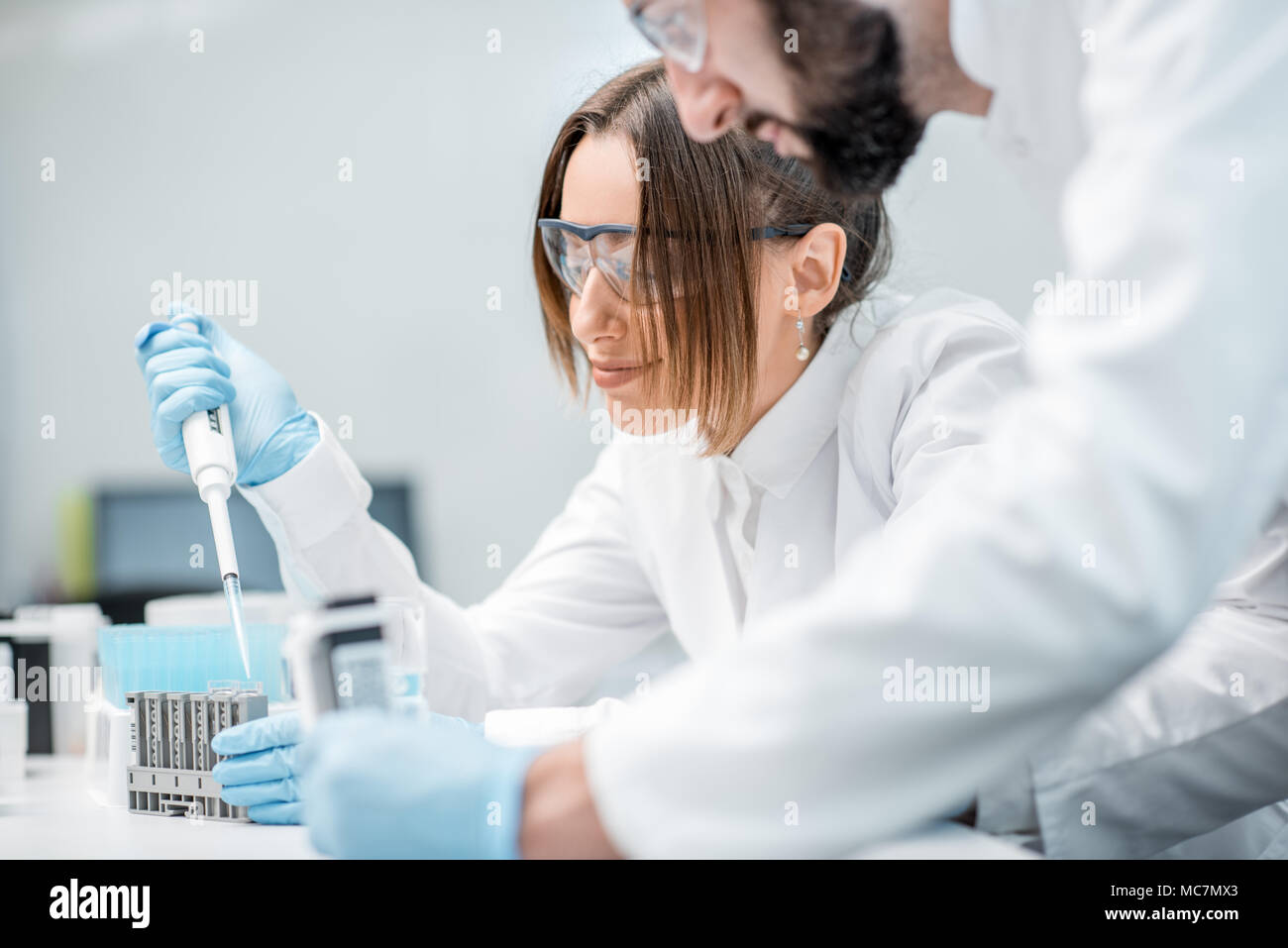 Laboratory assistants in uniform and protective glasses working with