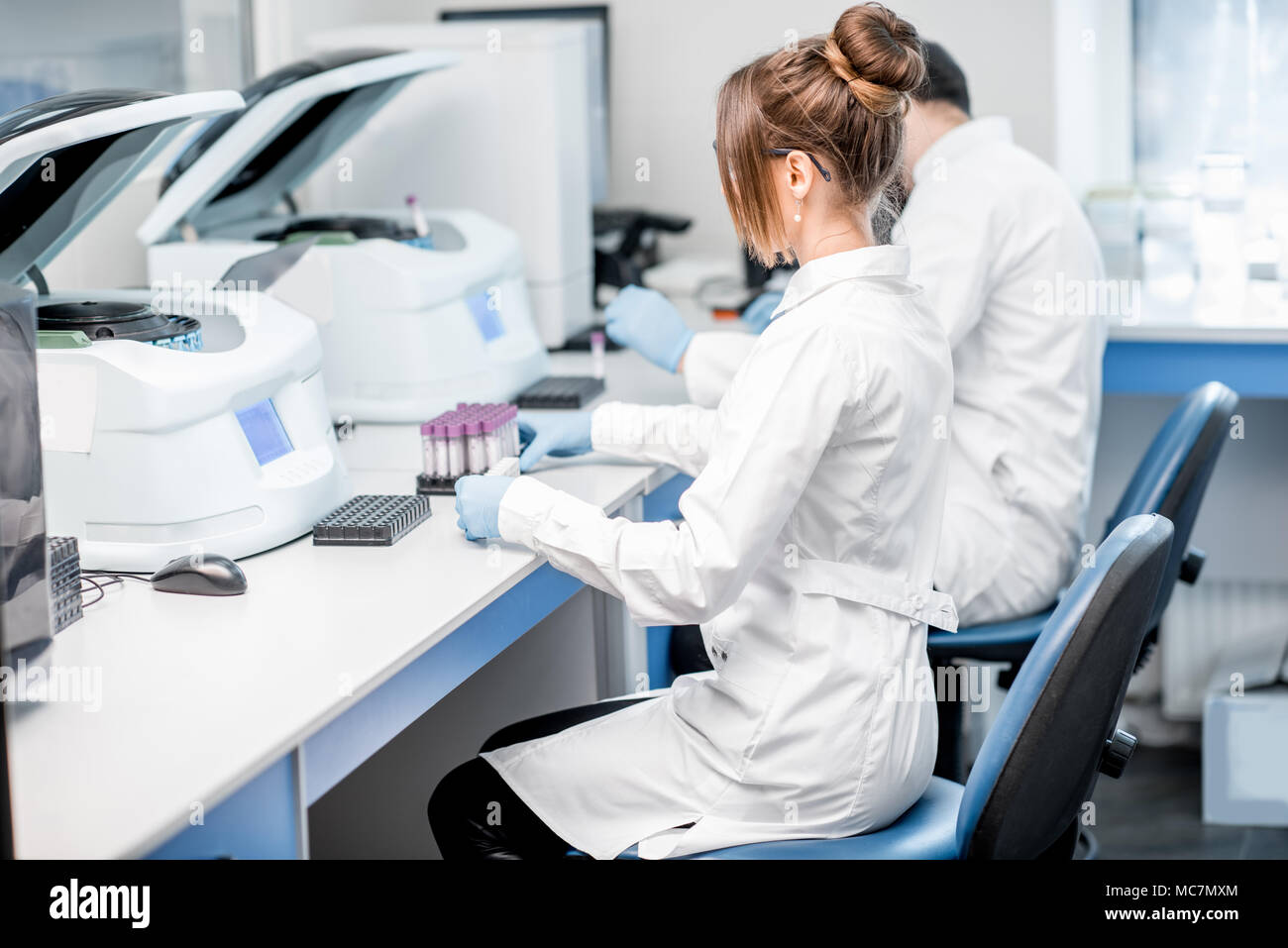 Laboratory assistants making analysis with test tubes and analyzer
