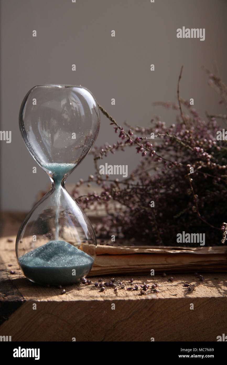 Time passing, sandglasses with blue sand, flowers, wood Stock Photo