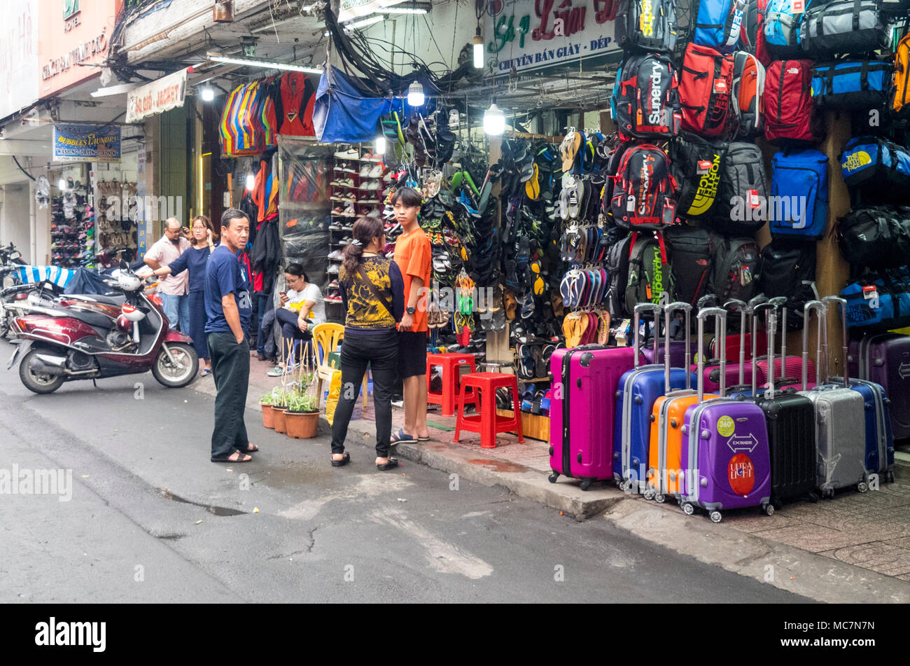 Shoppers standing on the sidewalk in front of shops selling, sportswear
